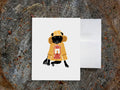 Greeting card with image of a dog with a yellow fisherman jacket holding a lantern.