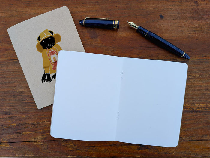 Open blank notebook with a pen and a pen on a wooden surface