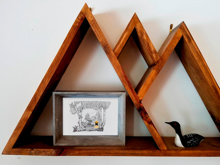 Framed illustration of a dog in a forest with a basket foraging for mushrooms a wood shelf.