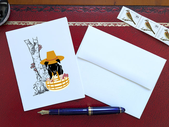 White card with drawing of dog holding basket with mushrooms on a red surface with a pen, envelope and stamp.