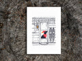 Art print featuring an illustration of a dog with red scarf and hat in a cabin covered in icicles, displayed on a wooden surface.