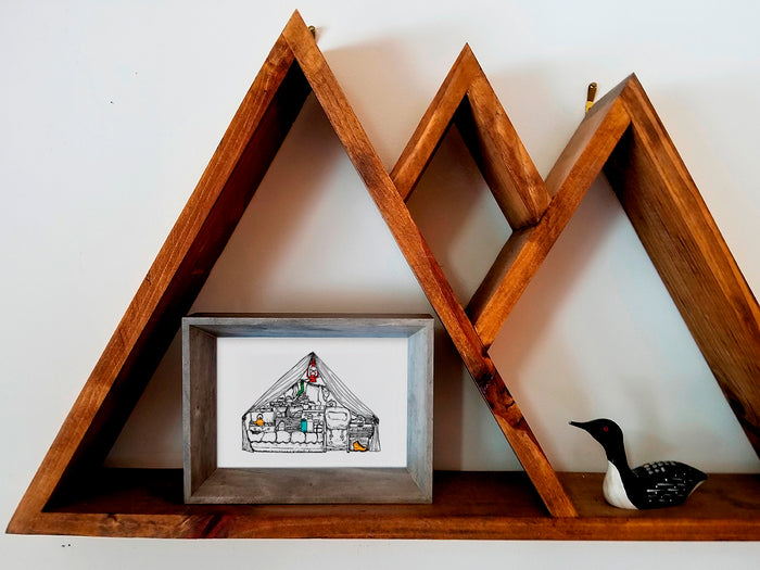 Framed illustration of a camping tent filled with gear on a wood shelf.