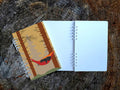 Notebook with a cover featuring a dog in a hammock on a wooden surface.