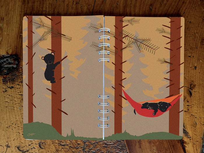 Notebook with bear and dog illustration on a wooden surface