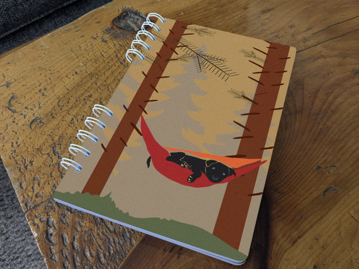 Notebook with a dog in a hammock design on a wooden surface