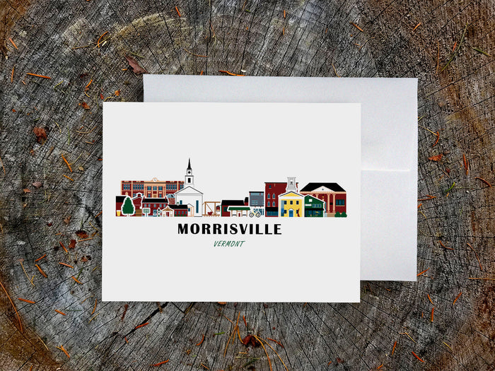 Greeting card with image of buildings arranged in a city skyline with the text Morrisville Vermont on a table with envelope.
