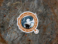 Sticker with a design of a dog and waves  looking through a porthole on a wooden background
